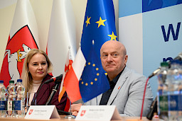 Ujęcie z bliska na Marszałka Jarosława Stawiarskiego oraz Dyrektor Annę Brzyską siedzących za stołem.