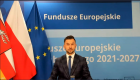 Mężczyzna siedzi przy stole, w tle flagi unie Europejskie, Polski i Województwa Lubelskiego.