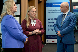Dyrektor Departamentu Zarządzania Programami Regionalnymi Anna Brzyska stoi w korytarzu z przedstawicielką Komisji Europejskiej Elżbietą Gajeską oraz mężczyzną.
