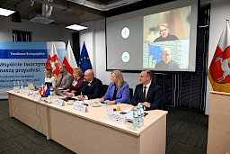 Wicemarszałek Województwa Lubelskiego Piotr Breś wraz z Dyrekcją Departamentu Zarządzania Programami siedzą przy długim stole. Wicemarszałek wypowiada się do mikrofonu prowadząc spotkanie.