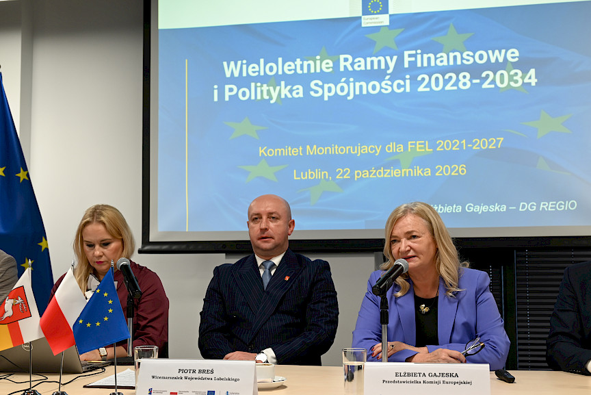 Przedstawicielka Komisji Europejskiej Elżbieta Gajeska wypowiada się do mikrofonu do uczestników posiedzenia. Obok niej siedzi Wicemarszałek Breś oraz Dyrektor Anna Brzyska.