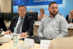 Ujęcie na dwóch mężczyzn siedzących na sali posiedzenia.