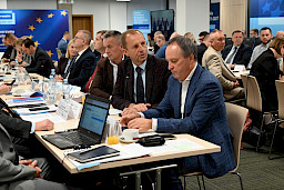 Duża liczba osób siedzących na sali przy stołach podczas posiedzenia Komitetu Monitorującego.