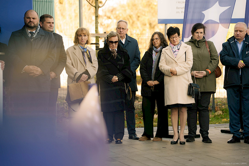 Ujęcie kilku osób stojących przed budynkiem.